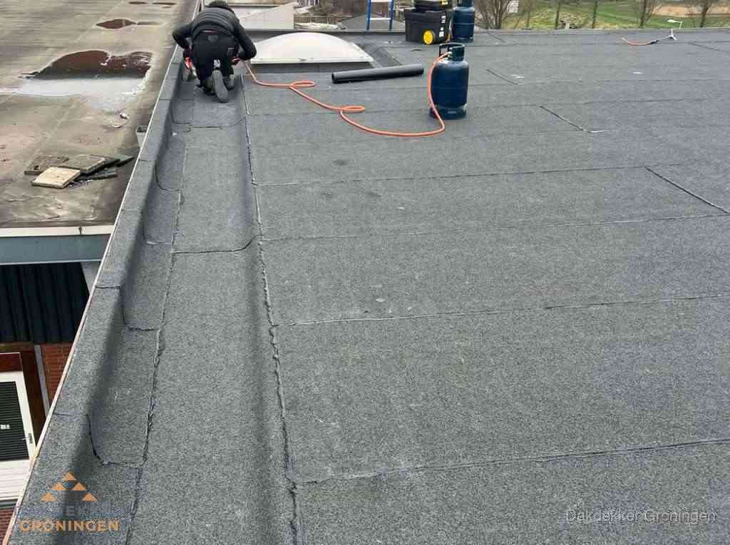 Dakdekker repareert bitumen dakbedekking op groot plat dak in Groningen Dakdekker repareert bitumen dakbedekking op groot plat dak in Groningen